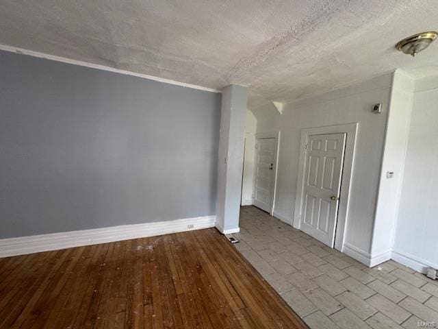 empty room featuring wood-type flooring, baseboards, and a textured ceiling