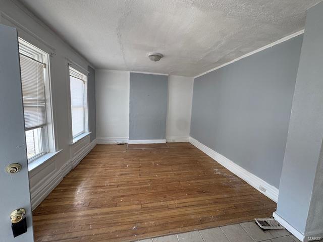 spare room featuring wood-type flooring, a textured ceiling, and baseboards