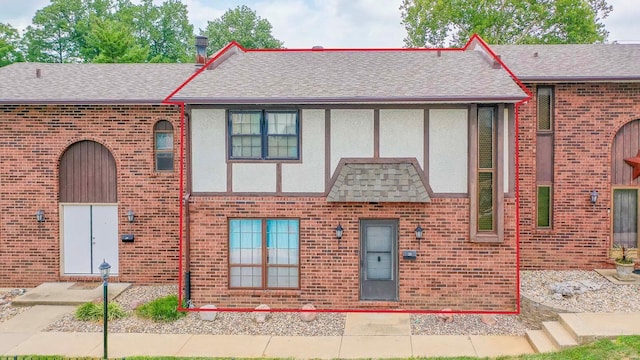 view of front of property with brick siding, roof with shingles, and stucco siding