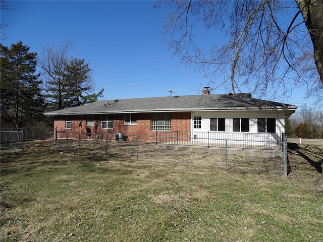 back of property with brick siding, a lawn, and fence private yard