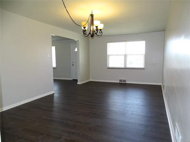 empty room featuring dark wood-style floors, visible vents, baseboards, and an inviting chandelier