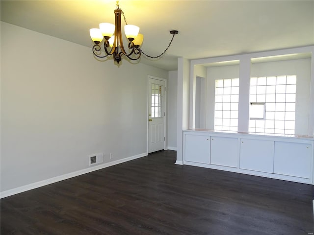 unfurnished room with visible vents, baseboards, an inviting chandelier, and dark wood-style flooring