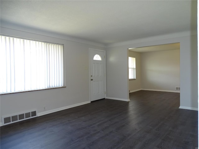 foyer featuring dark wood finished floors, baseboards, and visible vents