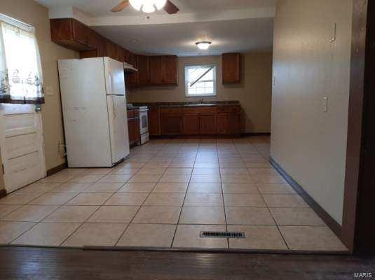 kitchen featuring ceiling fan, light tile patterned floors, a sink, stainless steel range oven, and freestanding refrigerator