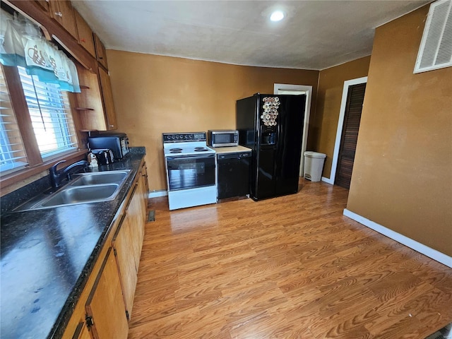 kitchen with visible vents, electric range oven, stainless steel microwave, black fridge, and a sink