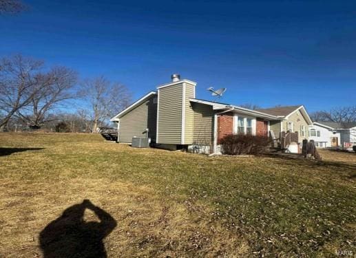 view of side of home with a chimney and a yard