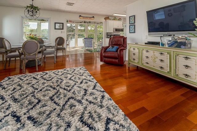 living area featuring a chandelier, visible vents, and wood finished floors