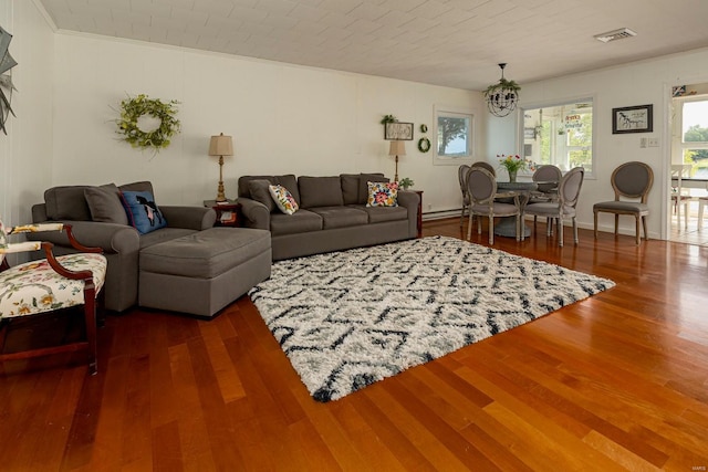 living room featuring a chandelier, visible vents, crown molding, and wood finished floors