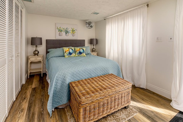 bedroom with wood finished floors, baseboards, a closet, and a textured ceiling