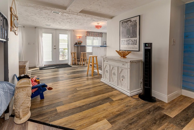 entrance foyer with french doors, baseboards, a textured ceiling, and wood finished floors