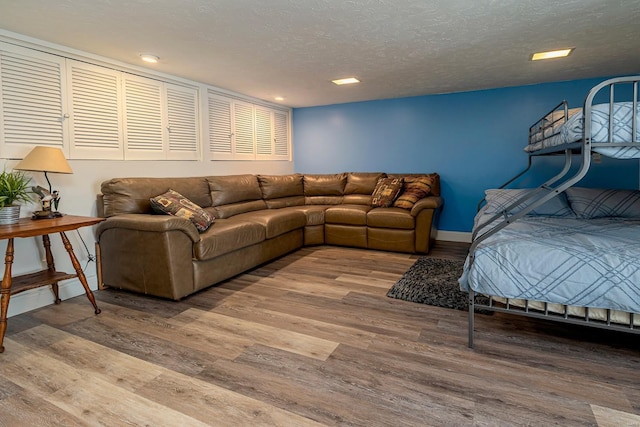 living area featuring baseboards, a textured ceiling, and wood finished floors