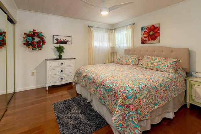 bedroom with a closet, crown molding, baseboards, and wood finished floors