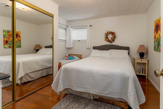 bedroom featuring a closet, crown molding, and wood finished floors