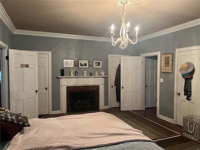 bedroom featuring a fireplace, ornamental molding, dark wood finished floors, and a chandelier