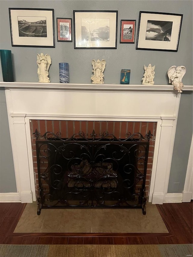 details featuring a brick fireplace and wood finished floors