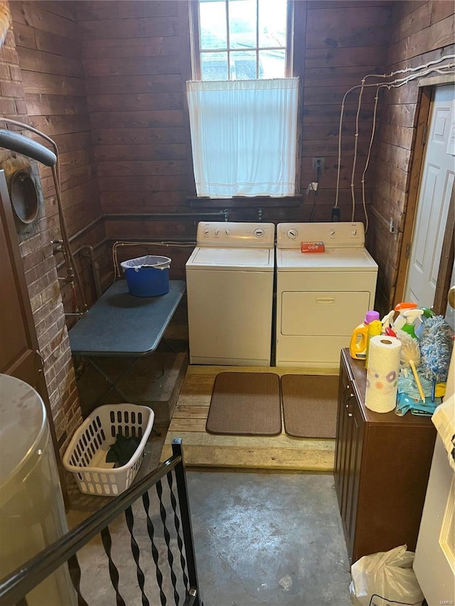 interior space featuring wood walls, unfinished concrete floors, and washer and clothes dryer