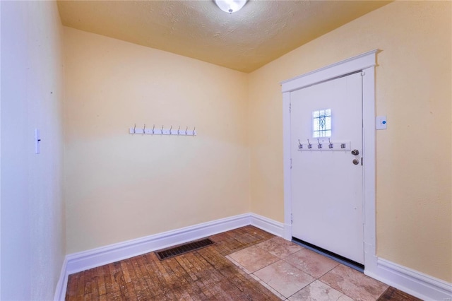 entryway with visible vents, baseboards, a textured ceiling, and hardwood / wood-style floors