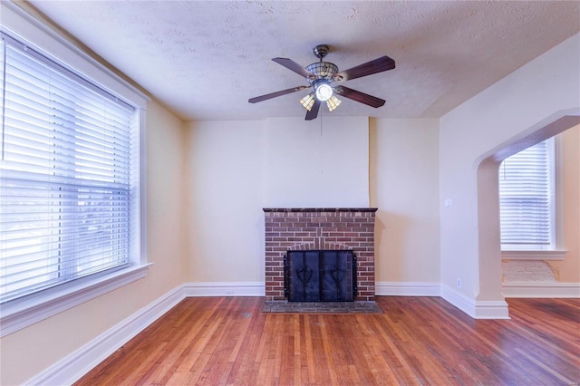 unfurnished living room with plenty of natural light, wood finished floors, and a fireplace