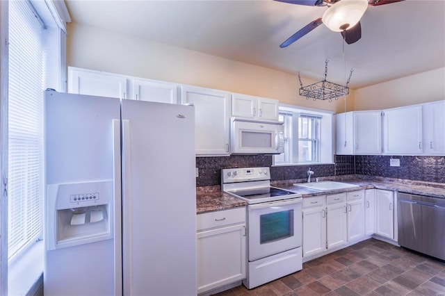 kitchen with backsplash, white appliances, white cabinetry, and a sink