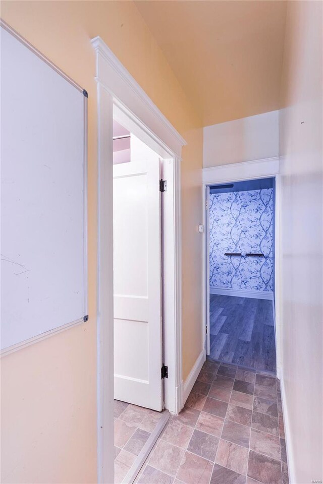 hallway featuring stone finish flooring and baseboards