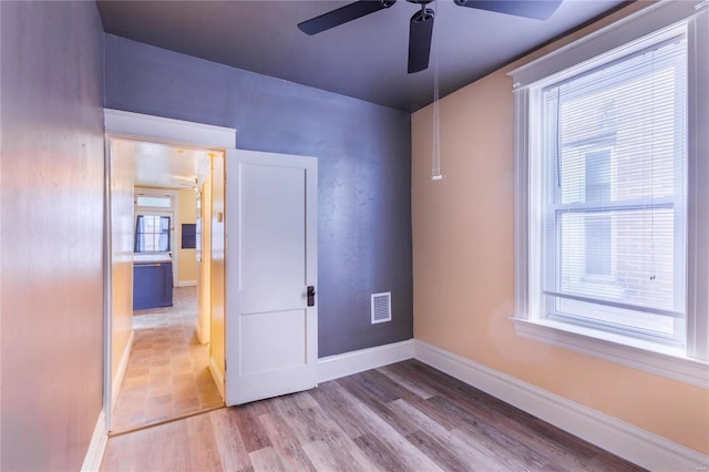 spare room with visible vents, a ceiling fan, baseboards, and wood finished floors