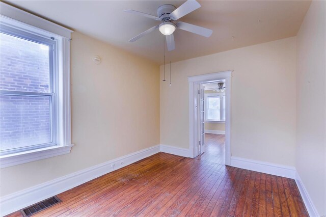 spare room with hardwood / wood-style floors, baseboards, visible vents, and ceiling fan