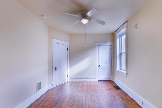 unfurnished room with baseboards, visible vents, wood-type flooring, and ceiling fan