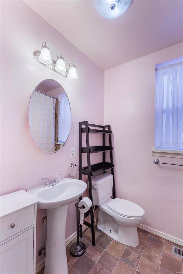 full bath featuring visible vents, baseboards, toilet, stone finish floor, and a sink