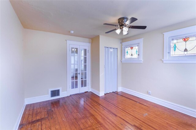 spare room featuring visible vents, baseboards, french doors, hardwood / wood-style flooring, and a ceiling fan