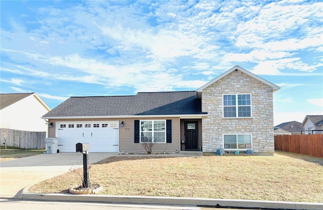 tri-level home featuring driveway, an attached garage, fence, and a front lawn