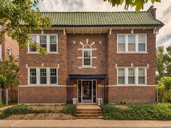 view of front of house featuring brick siding, a chimney, and a tile roof