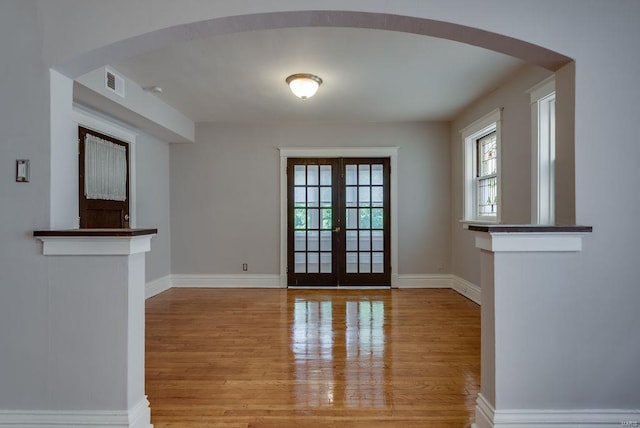 interior space featuring arched walkways, french doors, wood finished floors, and visible vents