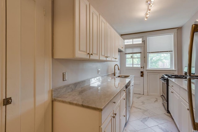 kitchen with stainless steel appliances, a sink, marble finish floor, light stone countertops, and track lighting