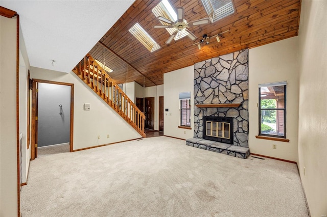 unfurnished living room with stairs, a skylight, carpet floors, and baseboards