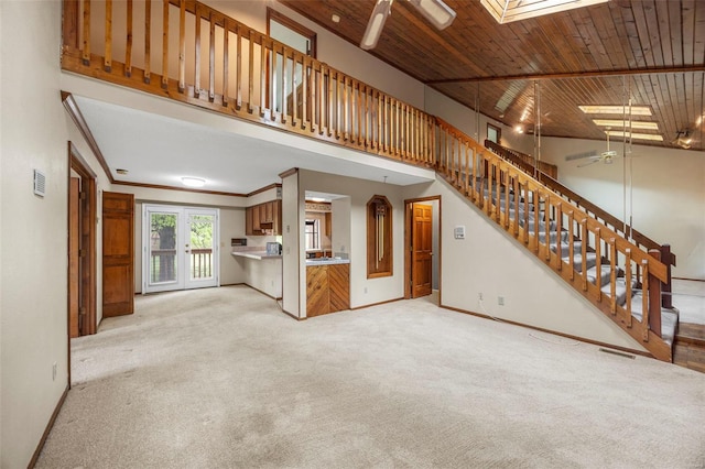unfurnished living room featuring visible vents, carpet floors, ceiling fan, a high ceiling, and stairway