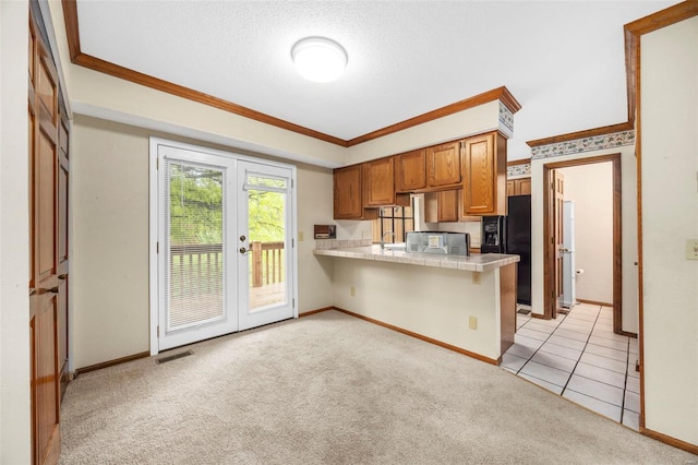 kitchen featuring french doors, brown cabinets, a peninsula, ornamental molding, and light carpet