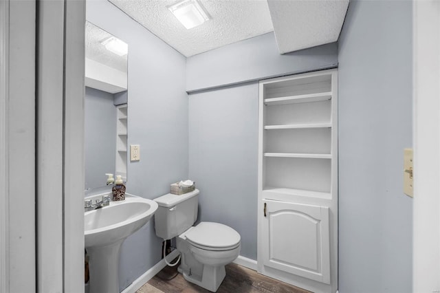 bathroom with toilet, a textured ceiling, and wood finished floors