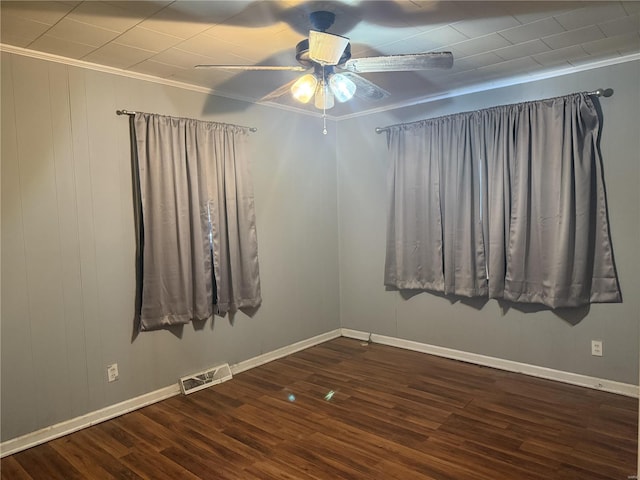 empty room featuring ornamental molding, dark wood-type flooring, visible vents, and a ceiling fan