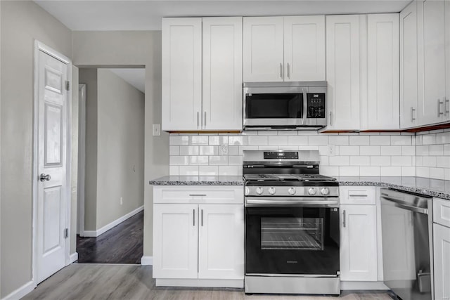 kitchen with stone counters, tasteful backsplash, appliances with stainless steel finishes, and white cabinetry