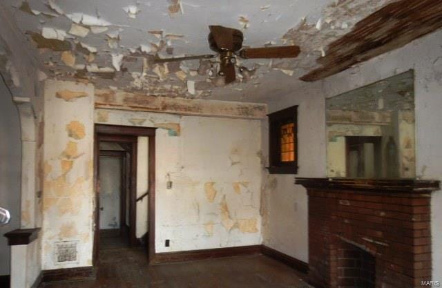 unfurnished living room with ceiling fan, a fireplace, baseboards, and visible vents