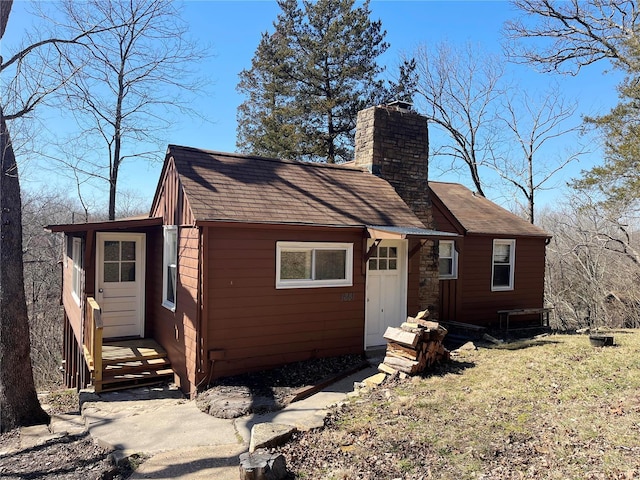 view of front of property featuring a chimney and a shingled roof