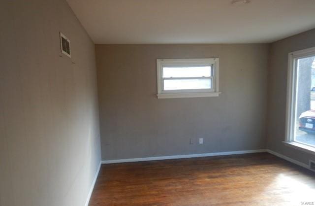empty room with a wealth of natural light, baseboards, and wood finished floors