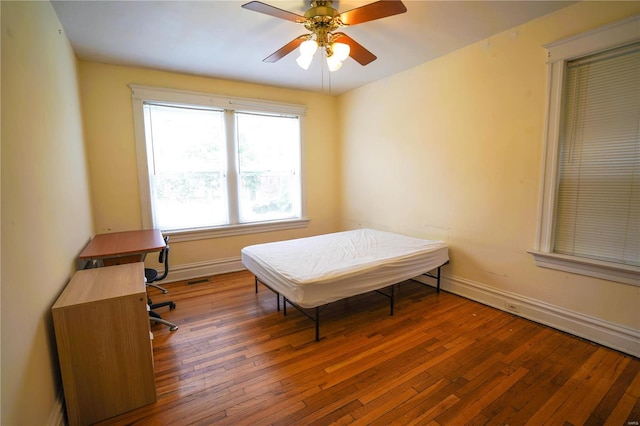 bedroom with ceiling fan, hardwood / wood-style flooring, and baseboards