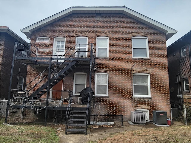 rear view of house with central air condition unit, stairway, and brick siding