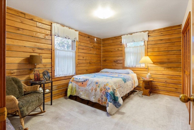 carpeted bedroom with wooden walls and a textured ceiling