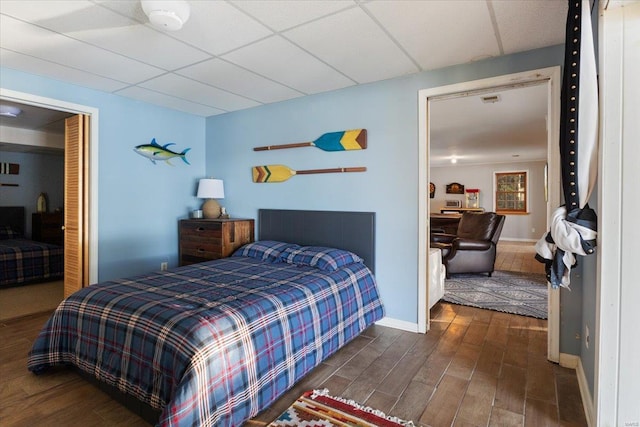 bedroom featuring wood finished floors, baseboards, and a paneled ceiling