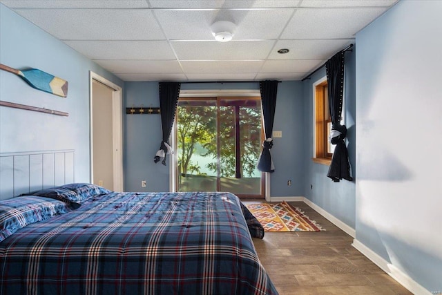 bedroom with a drop ceiling, baseboards, and wood finished floors