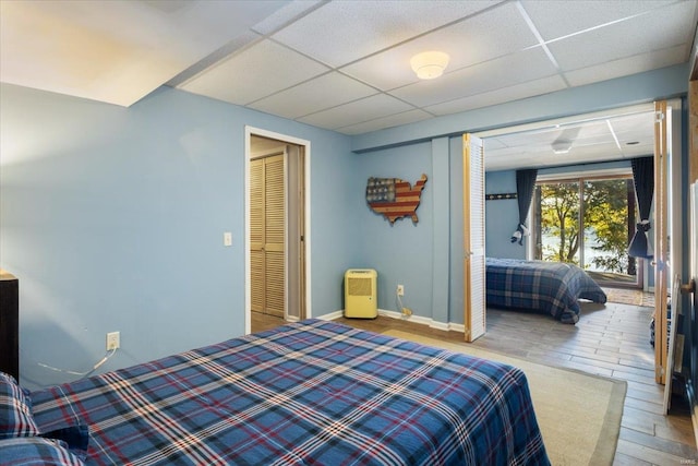 bedroom featuring a drop ceiling, baseboards, and wood finished floors