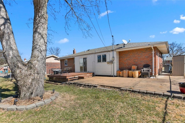 rear view of house featuring a patio, brick siding, a yard, a wooden deck, and a gate