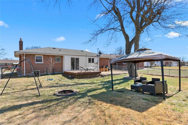 rear view of property featuring a lawn, a gazebo, an outdoor fire pit, fence, and a wooden deck